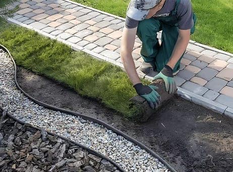 Pose de pavés sur une allée de jardin par un paysagiste.